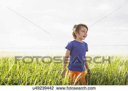 Boy (4-5) standing in grass and looking away View Large Photo Image Stock Image - Boy (4-5) standing in grass and looking away. Fotosearch