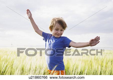 Boy (4-5) standing in grass with raised arms View Large Photo Image Stock Photograph - Boy (4-5) standing in grass with raised arms. Fotosearch