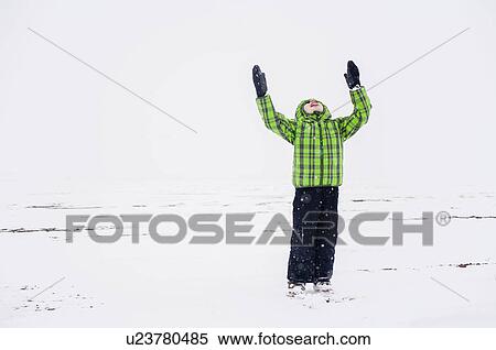 Stock Photography - Boy (4-5) with raised arms in snowy landscape. Fotosearch