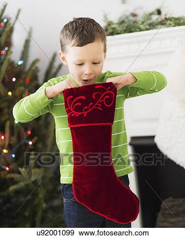 Boy (6-7) looking inside Christmas stocking View Large Photo Image Stock Photo - Boy (6-7) looking inside Christmas stocking. Fotosearch