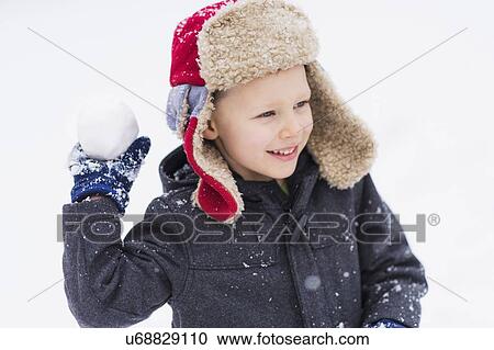 Stock Image - Boy (6-7) playing with snowball. Fotosearch