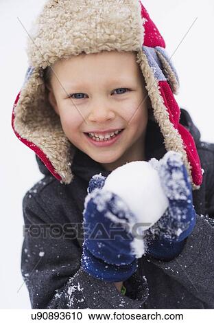Stock Image - Boy (6-7) playing with snowball. Fotosearch