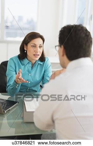 Stock Image - Businessman and businesswoman discussing in office. Fotosearch