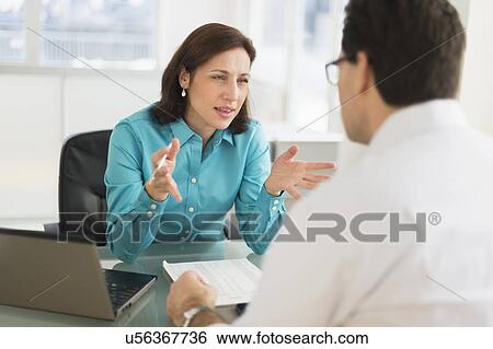 Stock Photograph - Businessman and businesswoman discussing in office. Fotosearch