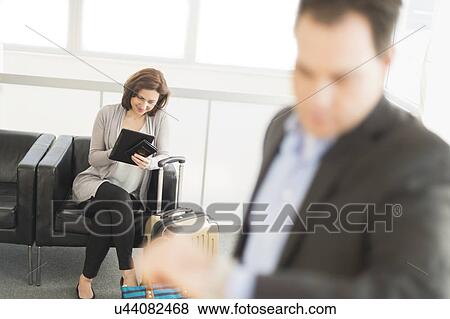 Businessman and businesswoman waiting for flight at airport View Large Photo Image Stock Photo - Businessman and businesswoman waiting for flight at airport. Fotosearch