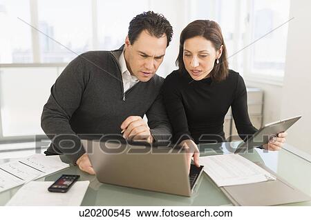 Stock Photography - Businessman and businesswoman working in office. Fotosearch