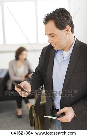 Picture - Businessman texting at airport. Fotosearch