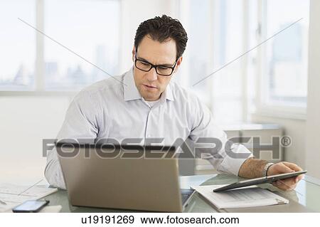 Stock Photo - Businessman using laptop and digital tablet. Fotosearch