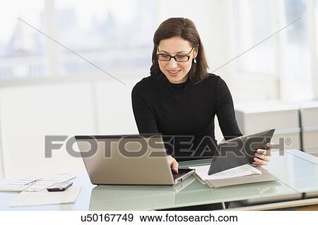 Businesswoman working on laptop and digital tablet View Large Photo Image Stock Photo - Businesswoman working on laptop and digital tablet. Fotosearch