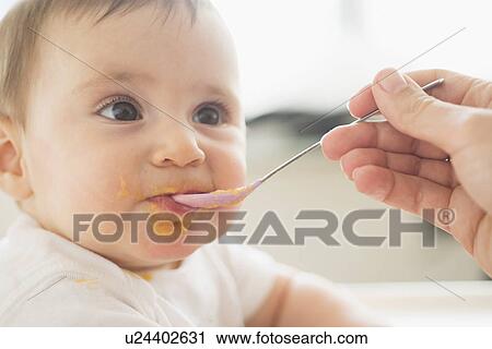 Close-up of baby girl (12-17 months) being spoon fed View Large Photo Image Stock Image - Close-up of baby girl (12-17 months) being spoon fed. Fotosearch