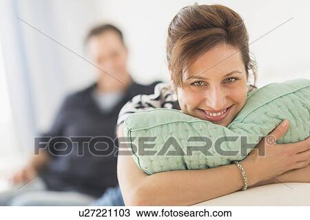 Stock Image - Couple relaxing in sofa, focus on woman. Fotosearch