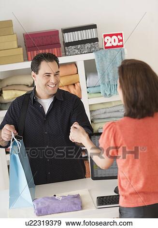 Stock Photo - Customer paying in clothes store. Fotosearch
