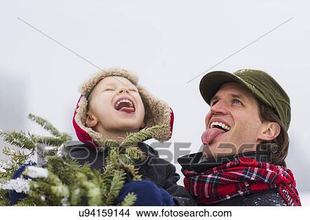 Father and son (6-7) catching snowflakes on tongue View Large Photo Image Picture - Father and son (6-7) catching snowflakes on tongue. Fotosearch