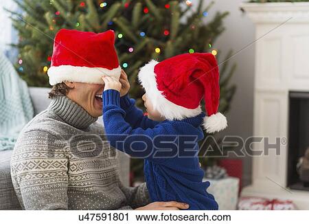 Stock Image - Father and son (6-7) playing next to Christmas tree. Fotosearch