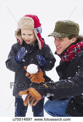 Stock Photo - Father and son (6-7) playing with snowball. Fotosearch