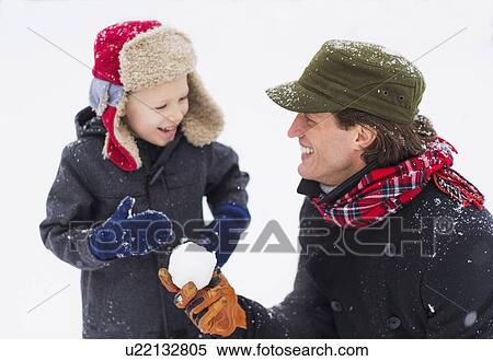 Stock Photography - Father and son (6-7) playing with snowball. Fotosearch