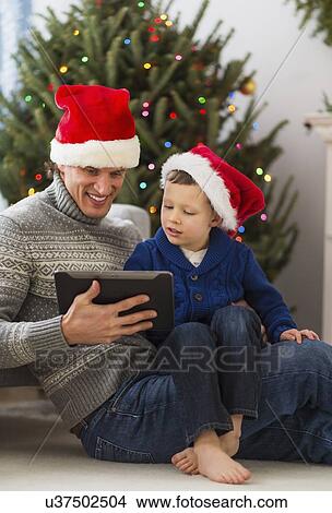 Picture - Father and son (6-7) using tablet. Fotosearch