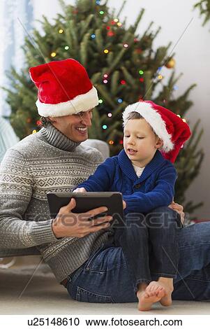 Stock Image - Father and son (6-7) using tablet. Fotosearch