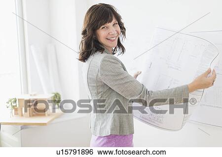 Stock Photograph - Female architect holding blueprints. Fotosearch