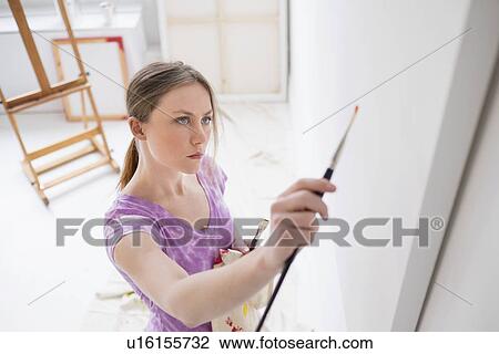 Stock Image - Female artist painting in studio. Fotosearch