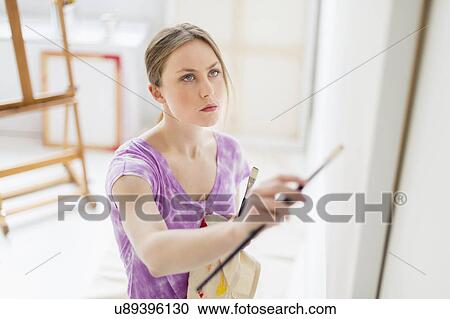 Stock Image - Female artist painting in studio. Fotosearch
