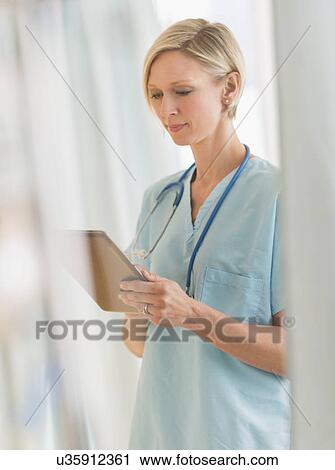 Stock Image - Female nurse using tablet PC. Fotosearch