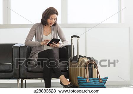 Stock Photo - Female tourist using tablet pc at airport. Fotosearch