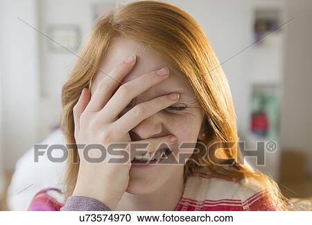 Stock Image - Front view of girl (12-13) with hand on head. Fotosearch