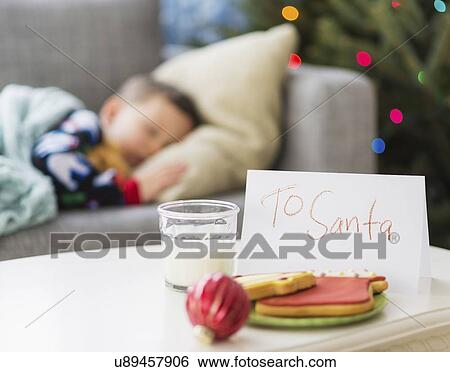 Stock Photograph - Gingerbread and glass of milk for Santa on foreground. Fotosearch