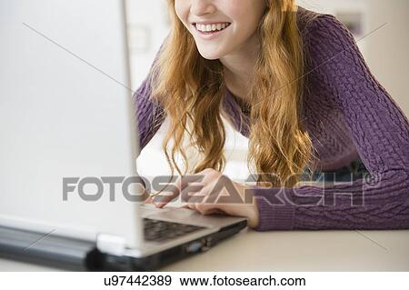 Stock Photo - Girl (12-13) using laptop, mid section. Fotosearch