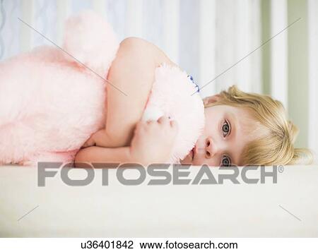 Stock Image - Girl (4-5) embracing soft toy. Fotosearch