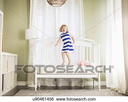 Stock Photograph - Girl (4-5) jumping on sofa. Fotosearch