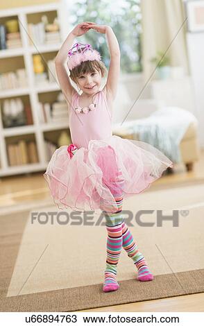 Stock Image - Girl (4-5) wearing tutu dancing in living room. Fotosearch