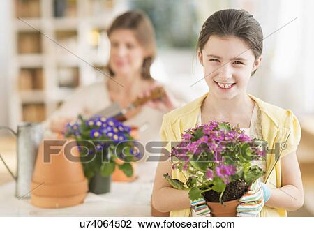 Stock Image - Girl (8-9) and mother potting flowers. Fotosearch