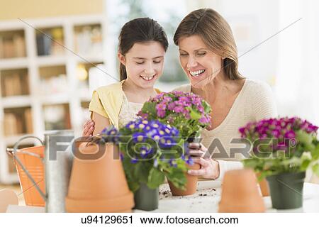 Stock Image - Girl (8-9) and mother potting flowers. Fotosearch