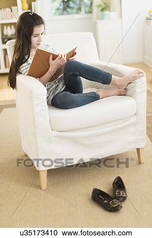 Girl (8-9) reading book in armchair View Large Photo Image Stock Image - Girl (8-9) reading book in armchair. Fotosearch