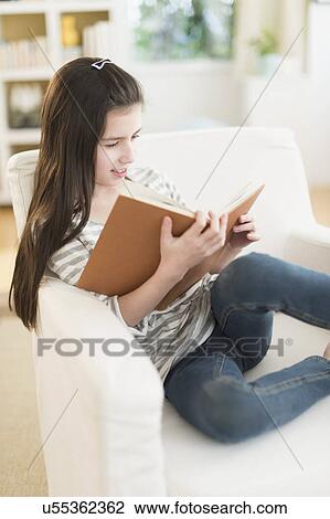 Girl (8-9) reading book in armchair View Large Photo Image Stock Image - Girl (8-9) reading book in armchair. Fotosearch