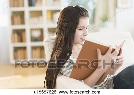 Girl (8-9) reading book in armchair View Large Photo Image Stock Photograph - Girl (8-9) reading book in armchair. Fotosearch