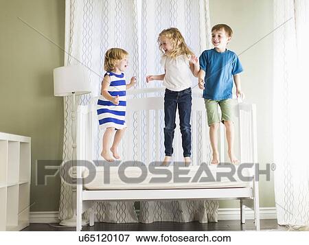 Girls (4-5, 6-7) and boy (8-9) jumping on sofa View Large Photo Image Stock Photo - Girls (4-5, 6-7) and boy (8-9) jumping on sofa. Fotosearch