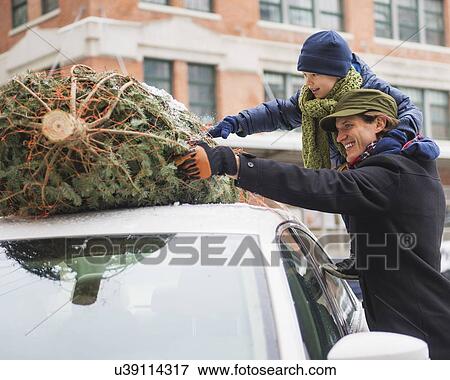 Stock Photo - Man with kid (6-7) bonding Christmas tree. Fotosearch