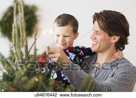 Man with kid (6-7) decorating Christmas tree View Large Photo Image Stock Image - Man with kid (6-7) decorating Christmas tree. Fotosearch
