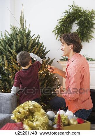 Man with kid (6-7) decorating Christmas tree View Large Photo Image Stock Photo - Man with kid (6-7) decorating Christmas tree. Fotosearch