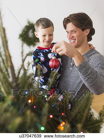 Man with kid (6-7) decorating Christmas tree View Large Photo Image Stock Photo - Man with kid (6-7) decorating Christmas tree. Fotosearch