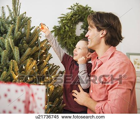 Man with kid (6-7) decorating Christmas tree View Large Photo Image Stock Photography - Man with kid (6-7) decorating Christmas tree. Fotosearch