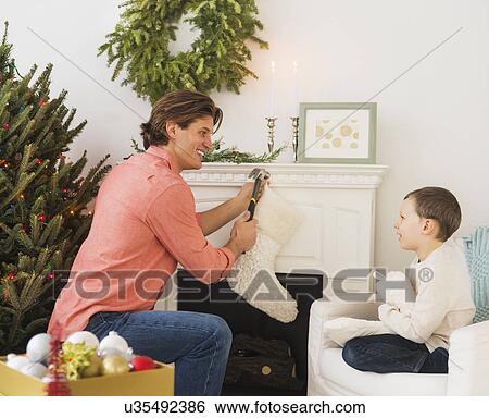Stock Photograph - Man with kid (6-7) decorating fireplace. Fotosearch