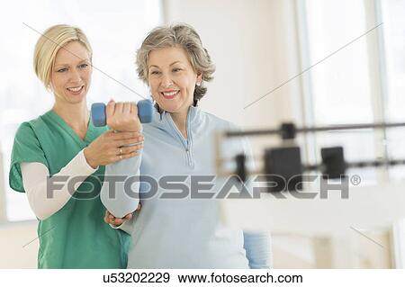 Stock Photo - Mature woman exercising with personal trainer. Fotosearch