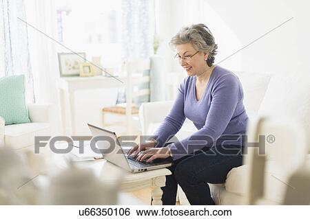 Stock Photograph - Mature woman paying bills via internet. Fotosearch