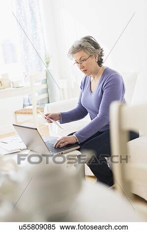 Stock Photography - Mature woman paying bills via internet. Fotosearch