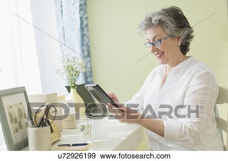 Stock Photo - Mature woman using tablet PC. Fotosearch