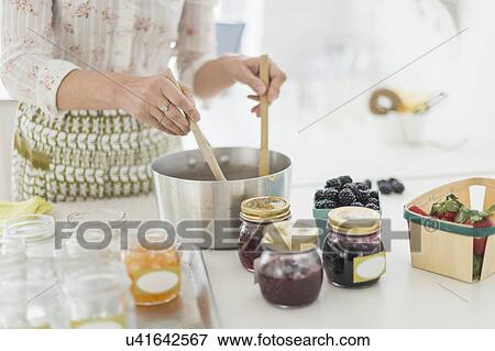 Stock Photo - Midsection of woman making preserves in kitchen. Fotosearch